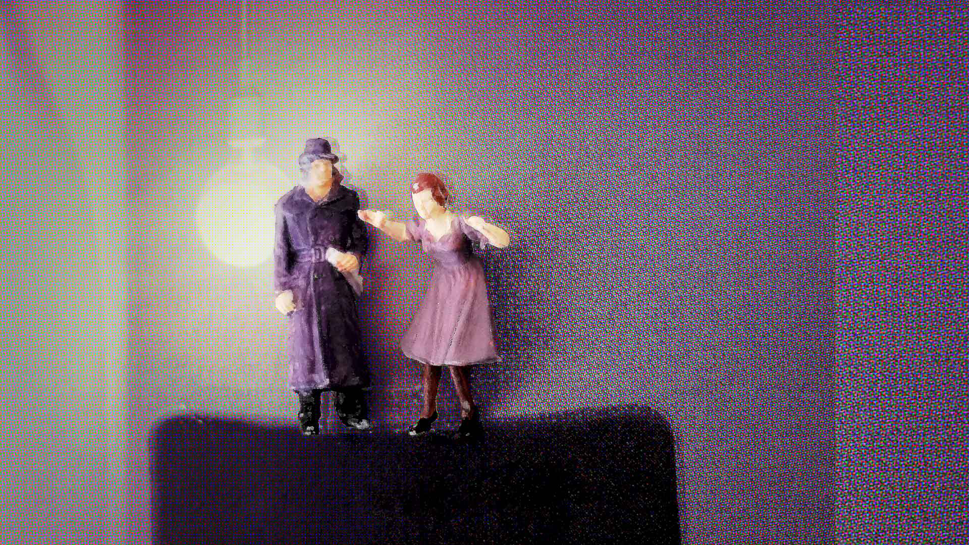 Zwei violette Modellfiguren stehen auf einem dunklen Sockel vor einer Wand, im Hintergrund leuchtet eine einzelne Glühbirne und wirft einen Lichtkreis.