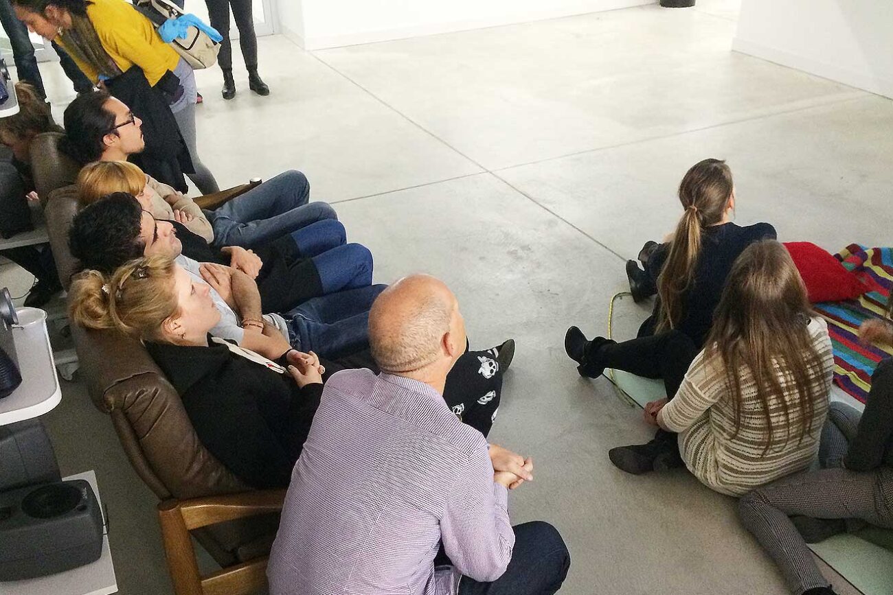 Publikum sitzt auf Sofas und Matten im Toni-Areal und verfolgt eine Präsentation des Projekts The Dreamy Island, projiziert von mehreren Beamern in den Ausstellungsraum.